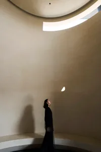 A minimalist interior space featuring natural light coming from a circular window.