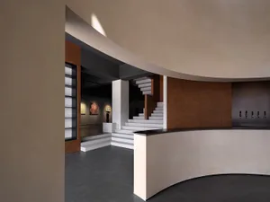 A modern architectural museum with concrete walls and a metal staircase.