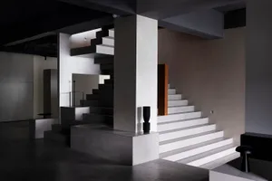 A minimalist interior design featuring concrete elements and industrial lighting.
