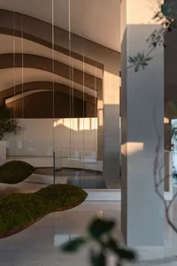 A modern interior design featuring a concrete-and-glass lobby with minimalist architectural elements and natural light.