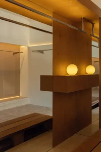 A minimalist wooden wardrobe interior featuring warm lighting and clean lines.