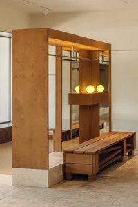Modern minimalist entryway featuring a wooden bench and mirrored closet