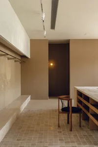 Interior of a minimalist office with concrete walls and floor, featuring a modern chair and desk setup.