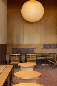 Modern cafe with wooden tables and benches, featuring a large spherical light fixture.