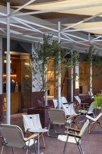 An outdoor seating area with modern white chairs and metal tables in a coffee shop interior.