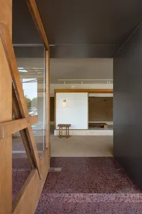 Modern residential entry with wooden columns and a concrete floor.