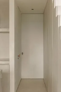 A minimalist doorway made of concrete with a simple wooden handle.