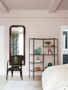 A modern minimalist bedroom with light-colored walls, metal shelving, and fabric curtains.