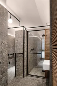 A modern bathroom with marble tiled walls and floor, featuring a glass shower enclosure.