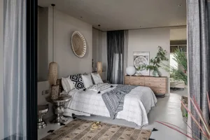 A modern bedroom featuring bohemian elements such as a patterned rug, decorative pillows, and natural wood furniture.