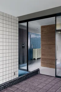 Modern bedroom featuring a wicker bed, blue tiles, and wood paneling.