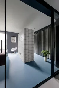 A modern bedroom with a gray tiled floor, white rocking chair, and gray curtains.