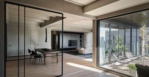 Contemporary residential interior featuring hardwood flooring and floor-to-ceiling windows.