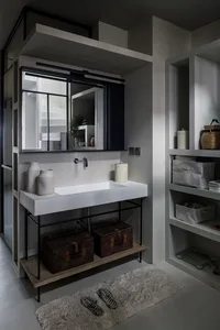 A modern minimalist bathroom with a concrete sink, metal faucet, and woven baskets under the counter.