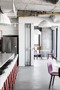 Modern minimalist co-working space with concrete walls, stainless steel appliances, and industrial-style bar seating.