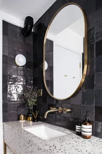 Modern black and white bathroom with a terrazzo countertop and brass fixtures.