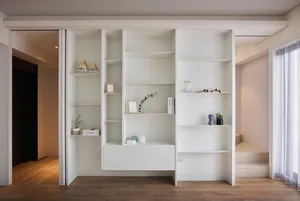 A minimalist living room with a white floating entertainment center displaying various decorative items, set against a wooden