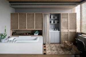 Industrial-style bathroom featuring wooden cabinets, ceramic fixtures, and a rattan rug on hardwood floors.