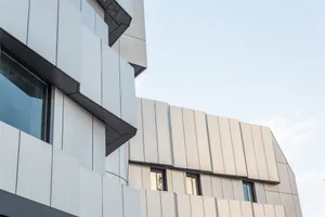 Modern buildings featuring metal cladding surfaces against a clear sky.