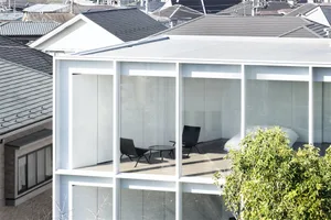 A modern glass terrace with white exterior and black furniture.
