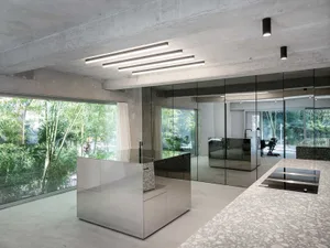 A modern industrial living room with concrete walls and ceiling, large windows, and minimalist furniture.