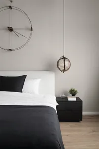 A minimalist bedroom featuring a black and white color scheme with a bed, black headboard, and white bedding, along with a mo