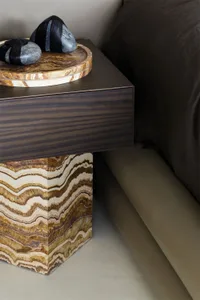 A minimalist bedroom featuring a stone bedside table with a dark wood drawer.