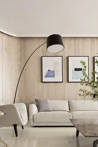 A minimalist living room with a beige sofa, modern floor lamp, and abstract wall art.