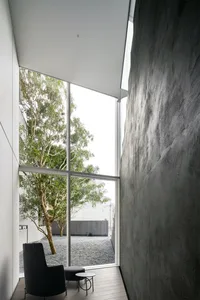 A minimalist residential interior featuring concrete walls and large glass window.