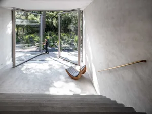 Concrete stairs with a modern, minimalist design, featuring an open-air entrance leading to a garden.