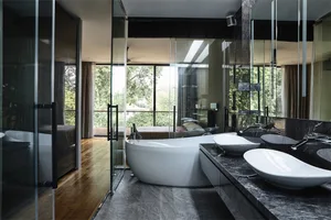 A modern bathroom interior featuring a concrete bathtub, marble countertops, and large windows overlooking greenery.