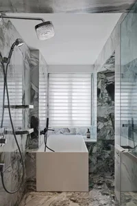 Modern bathroom with marble walls and floor, featuring a freestanding bathtub and a walk-in shower.
