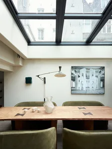 Modern dining room with wooden table and chairs, featuring a large window with city view and abstract painting on the wall.