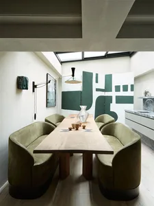 A modern dining room with wooden furniture, featuring green upholstered chairs and a wooden table.