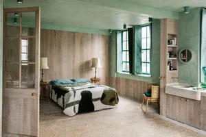A modern bedroom with green sheeting, wood paneling, and a stone sink.
