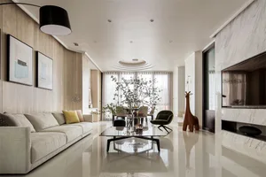 A modern living room featuring marble flooring, a large beige sofa, and a contemporary coffee table with greenery.