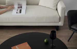 A modern living room with a white sofa, black coffee table, and black leather chair.