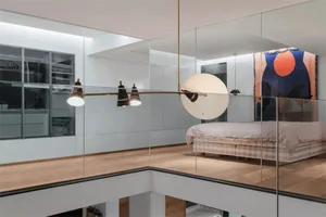 A modern minimalist bedroom with a glass wall, showcasing a single bed and minimal decor.