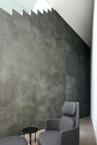 Modern minimalist room featuring textured concrete walls and a single chair in a minimalist interior design setting.