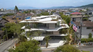 A modern, multi-level residential building with glass walls and a concrete exterior.