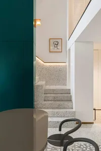 Modern staircase with speckled white terrazzo tiles, white walls, and a black chair.