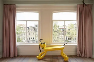 A bright living room interior design featuring pink curtains, wooden floors, and a glass window frame.