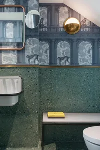 Modern bathroom with terrazzo tiles, a floating vanity, and a gold sconce.