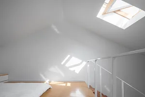 Modern bedroom with a white concrete wall and floor features a bed with a minimalist design.