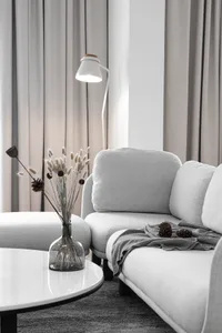Modern grey living room with minimalist design, featuring a comfortable textile sofa, glass vase with dried flowers, and a sl