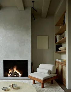 A modern living room with concrete walls, wood furniture, and a fireplace.