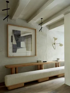 A modern living room featuring wooden furniture, concrete walls, and textured surfaces.