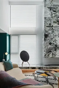 Modern living room featuring marble and glass materials, with metal accents and a wool blanket.