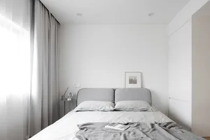 A minimalistic bedroom featuring a bed with soft textiles and a simple, elegant design.
