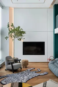 A minimalist living room with a wood floor, an armchair, a coffee table, a rug, and a fireplace.
